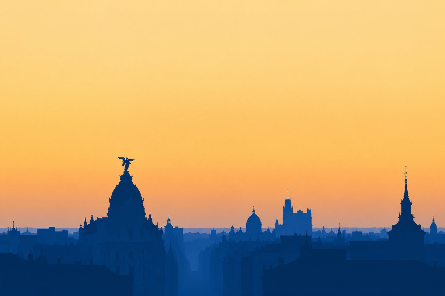 Golden hour over central Madrid, with the rooftops of the old city and a grand boulevard under a warm sky.
